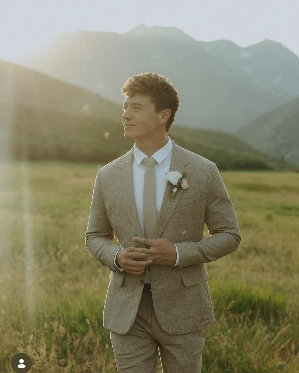 Cole Johnstone in a meadow with the mountains behind